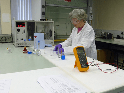 NEC tutor Jane Blunt testing the electrochemical charge of a variety of colourful chemicals in solution under laboratory conditions