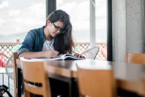 Female student studying with book and pen on a desk.