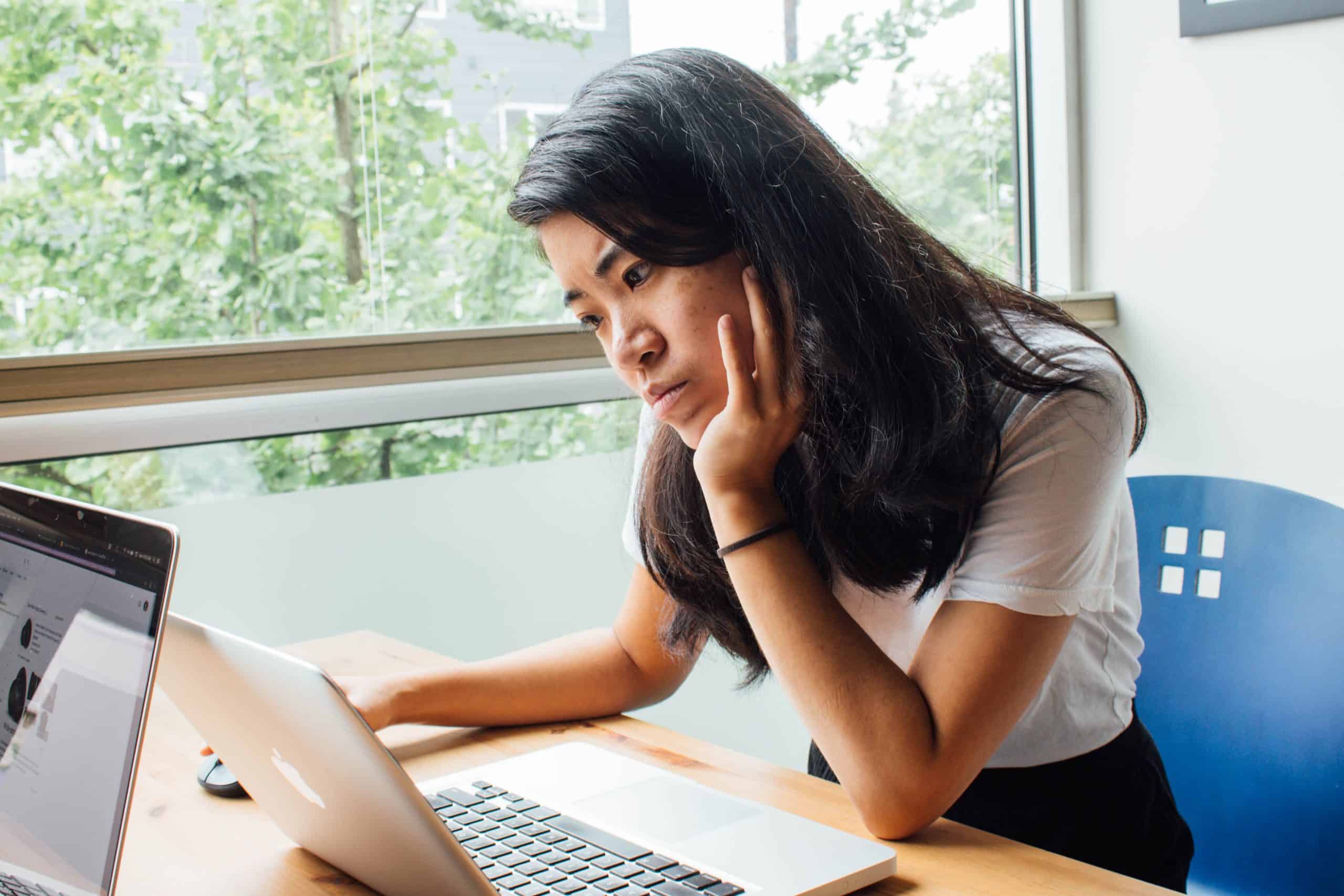 young female hunched over a desk and laptop