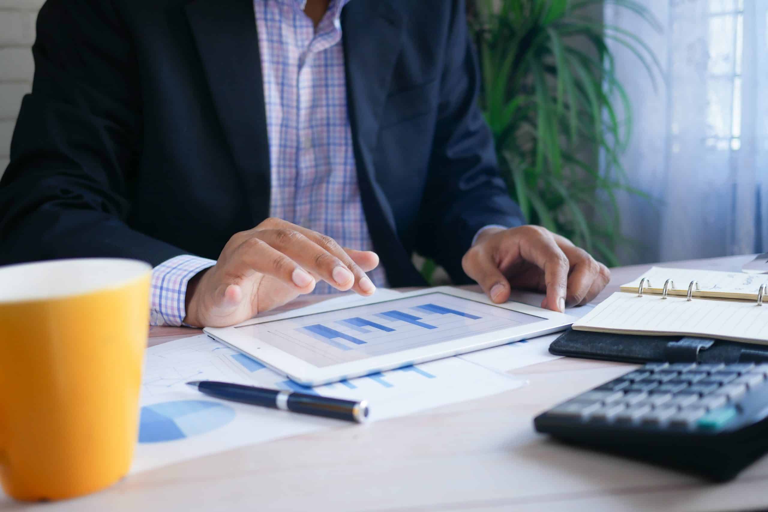 man in suit at desk with paper work and a yellow mug