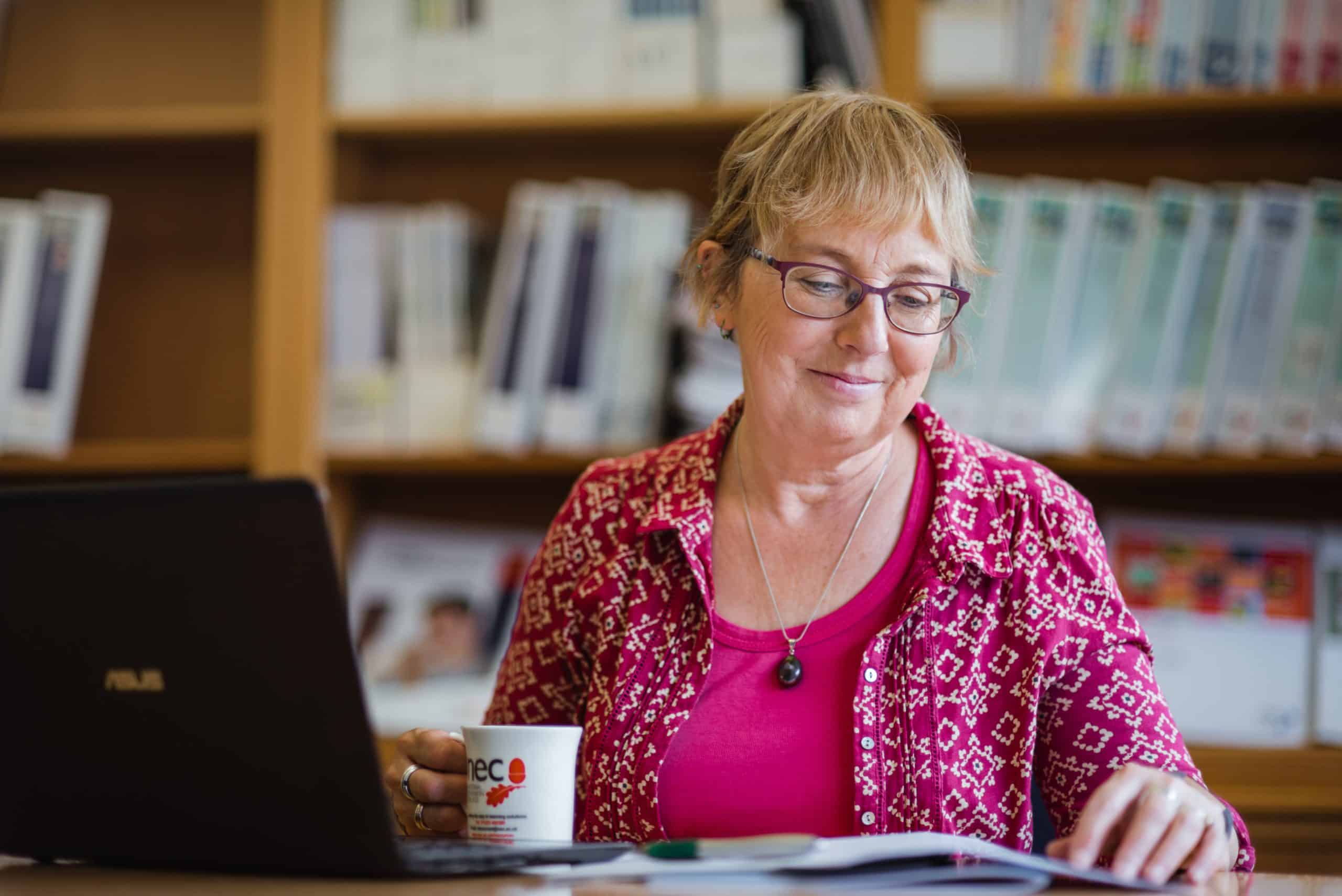 friendly NEC employee at desk. Ready to help NEC distance learning students with their online study