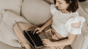 female sitting on sofa on laptop, looking at NEC's learning design