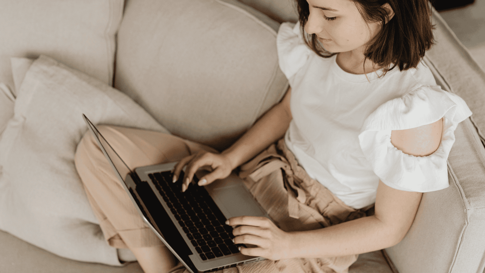 female sitting on sofa on laptop, looking at NEC's learning design