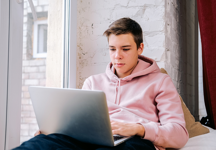 student studying from laptop in window