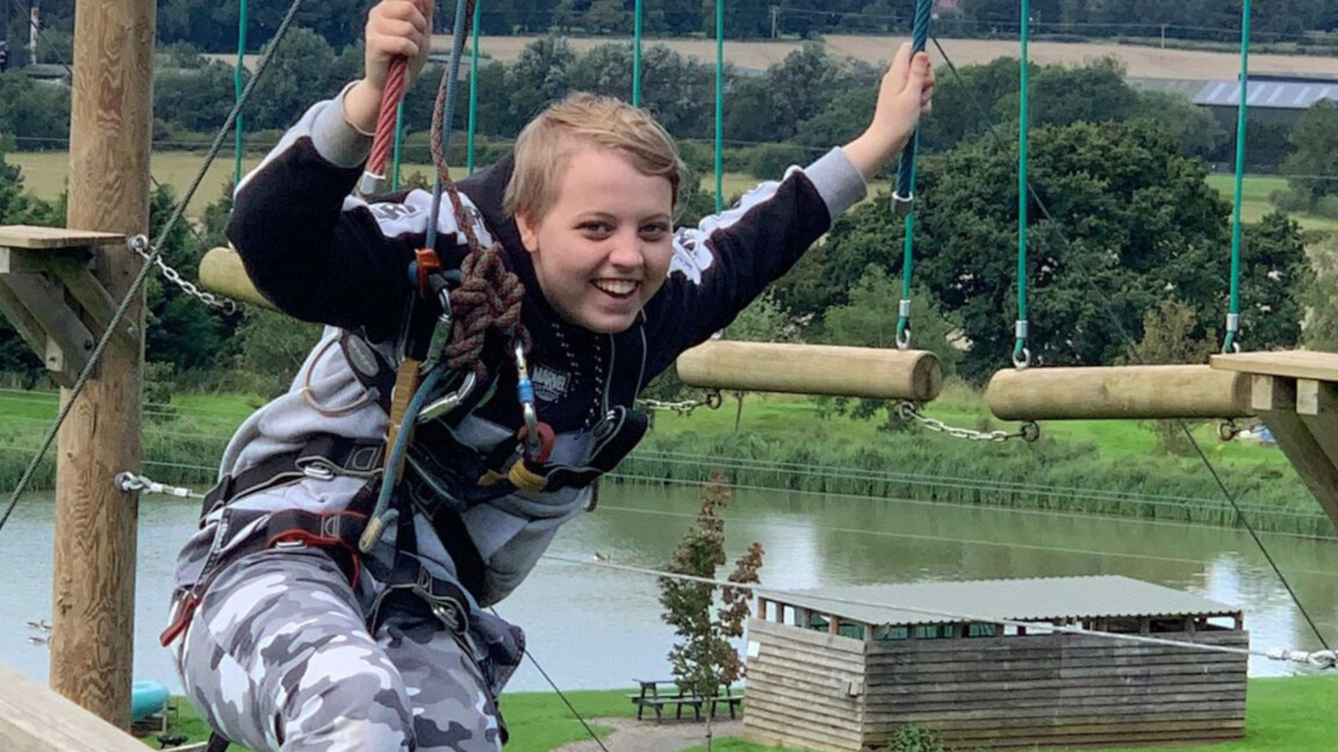 A teenage girl smiling on a high ropes adventure course, wearing a safety harness, representing the freedom and confidence that flexible homeschooling provides for ambitious young learners.
