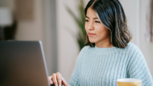 A focused student works at a laptop with a slight smile, suggesting confidence and concentration—symbolising flexible, independent study in subjects like A level Business or Economics.