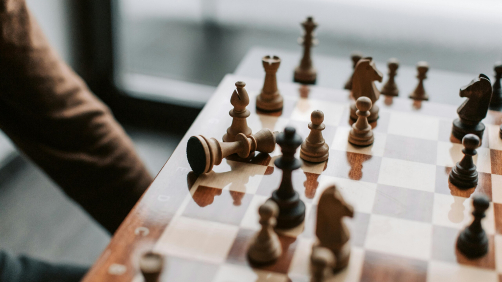 A close-up of a chessboard mid-game with a toppled king—symbolising deep thinking, strategic analysis, and the philosophical themes of logic, consequence, and decision-making. Symbolising A level Philosophy