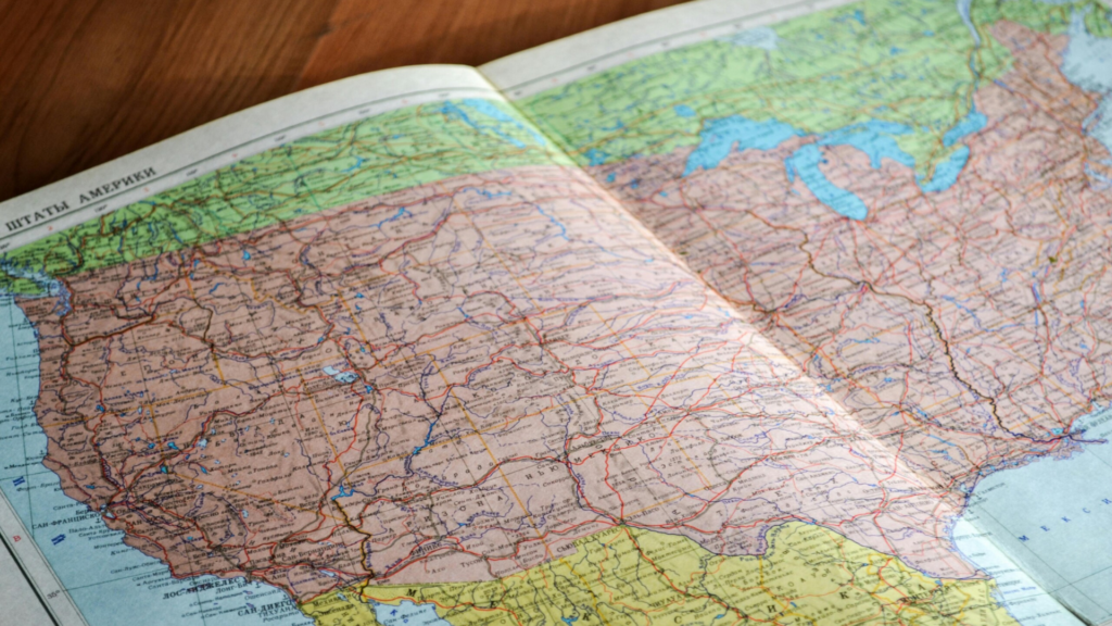 A detailed map of the United States with Russian labels, spread open on a wooden table—symbolising global awareness, spatial understanding, and geographical exploration.
