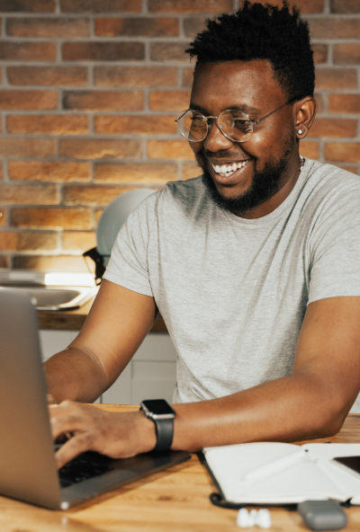 Smiling tutor sits at his laptop, typing