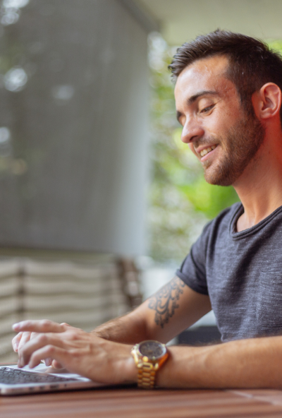 Tutor sits typing into his laptop, smiling