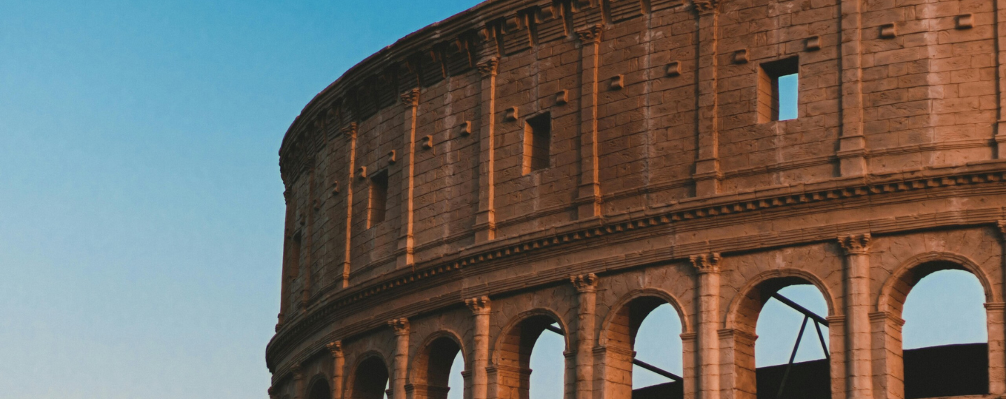 A close-up view of the ancient Roman Colosseum under a clear blue sky, showcasing its iconic arches and stone architecture.