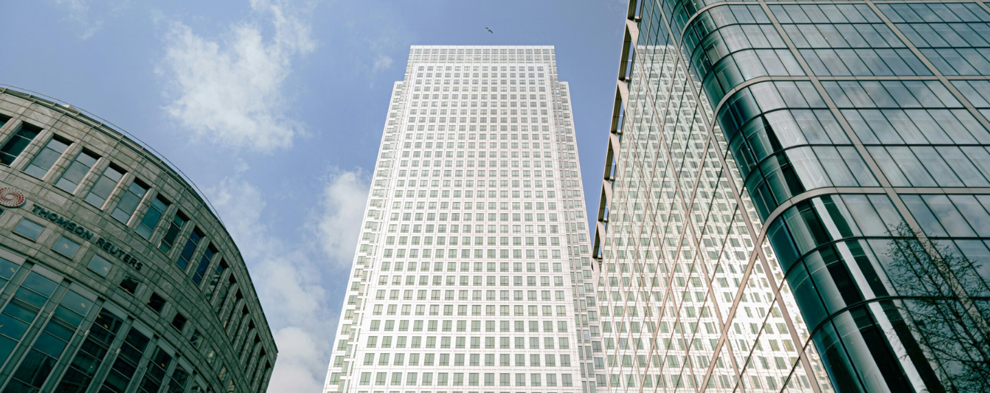 Upward view of modern glass office buildings in a financial district, symbolising global economics, trade, and business activity.