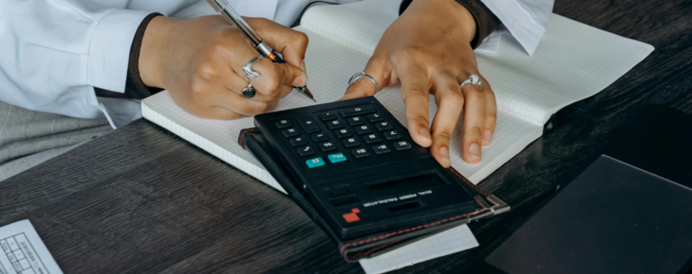 Close-up of a student using a calculator while writing in a squared notebook, representing advanced mathematical problem-solving.