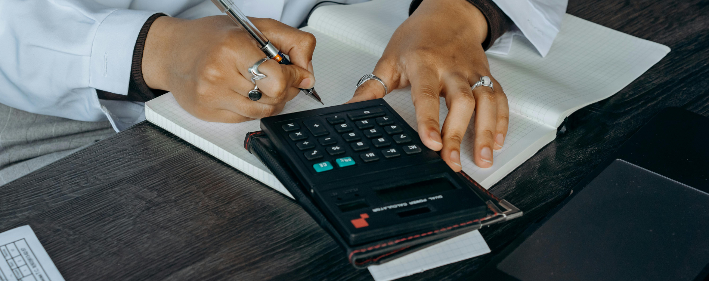 Close-up of a student using a calculator while writing in a squared notebook, representing advanced mathematical problem-solving.