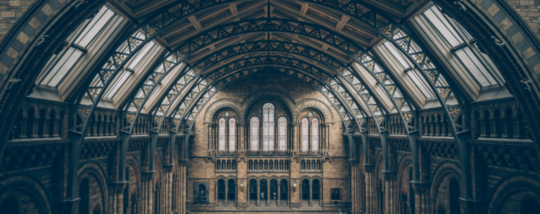 Interior view of a grand historical building with arched architecture and stained-glass windows, representing the study of history and heritage.