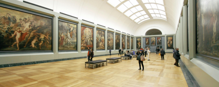 Visitors walking through an art gallery with large classical and Renaissance paintings displayed on both sides, representing the study of art history and visual culture.