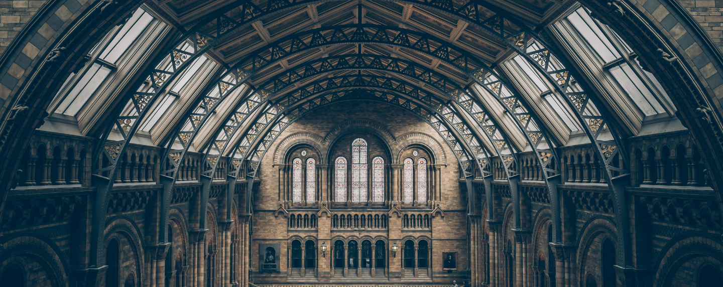 Interior view of a grand historical building with arched architecture and stained-glass windows, representing the study of history and heritage.