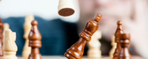 Close-up of chess pieces mid-move on a board, symbolising strategic thinking, logic, and philosophical decision-making.