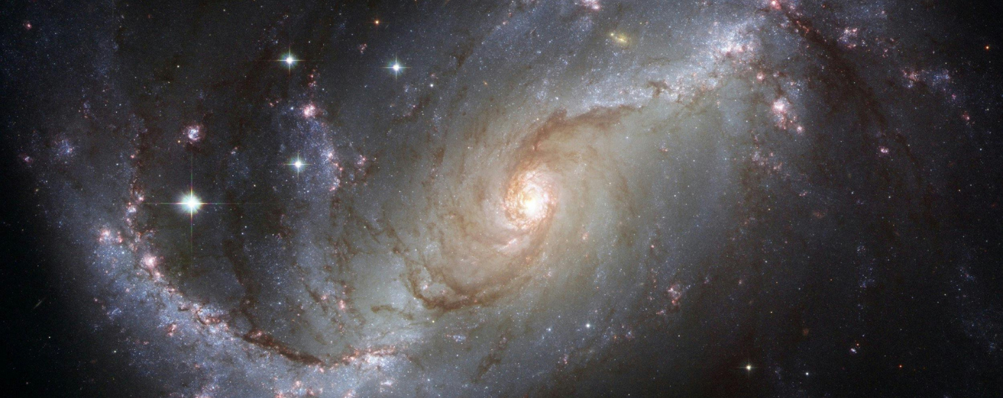 A detailed image of a spiral galaxy in deep space, showing stars, cosmic dust, and glowing light—representing the study of astrophysics and the universe.