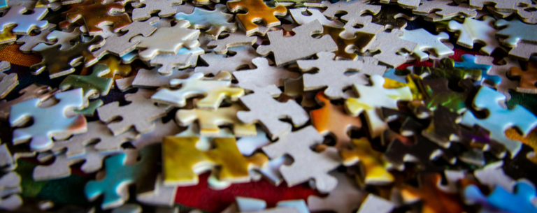 Close-up of colourful jigsaw puzzle pieces scattered on a surface, symbolising the complexity and interconnection of the human mind in psychology.