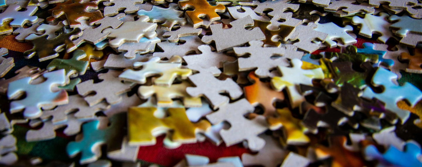Close-up of colourful jigsaw puzzle pieces scattered on a surface, symbolising the complexity and interconnection of the human mind in psychology.