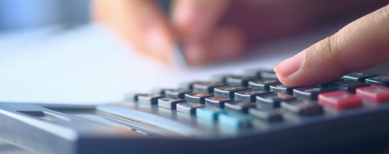 Close-up of a hand pressing buttons on a calculator with blurred background, symbolising mathematical calculations and academic study.