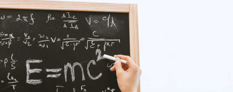 Close-up of a hand writing E=mc² on a chalkboard, surrounded by physics formulas and scientific notations.