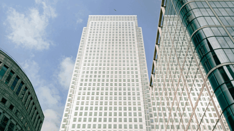 Upward view of modern glass office buildings in a financial district, symbolising global economics, trade, and business activity.