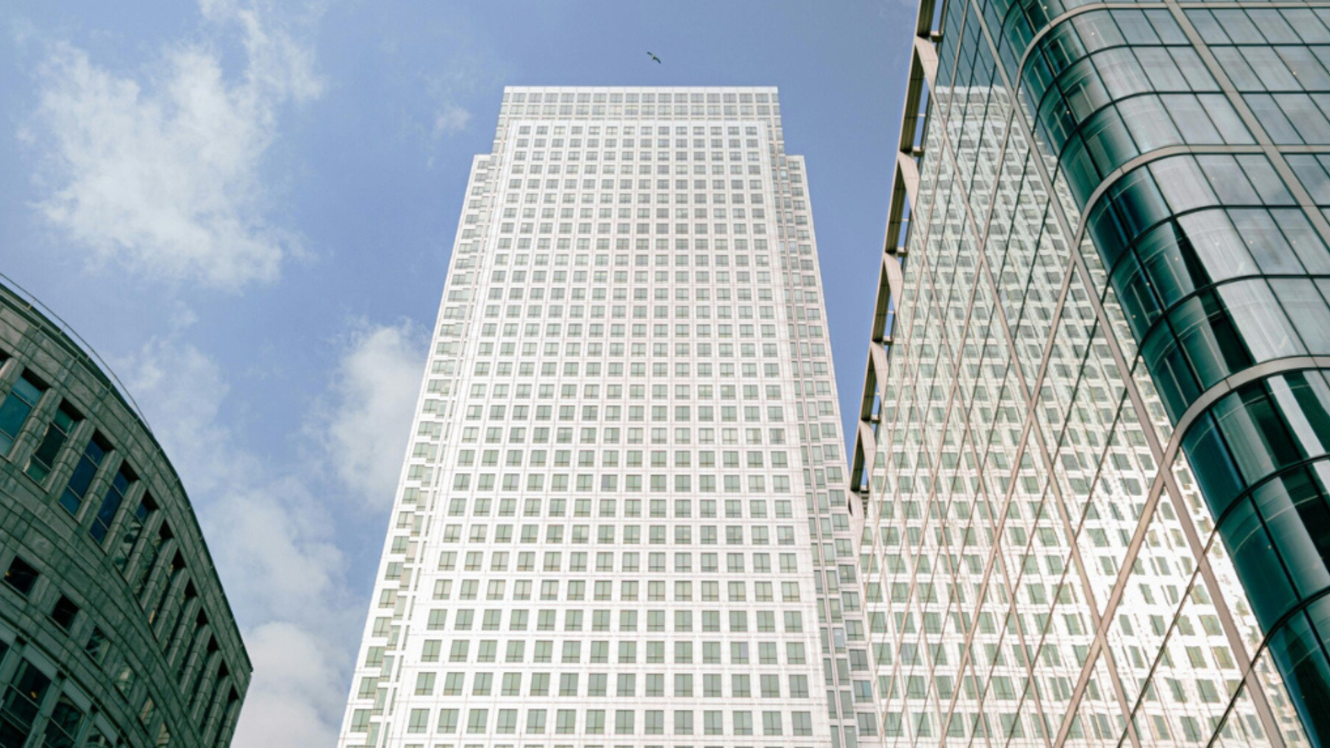 Upward view of modern glass office buildings in a financial district, symbolising global economics, trade, and business activity.