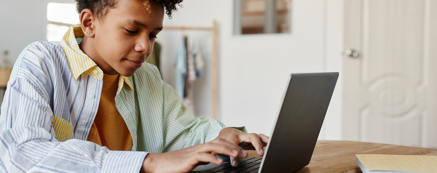 teenage boy sits at home using a laptop