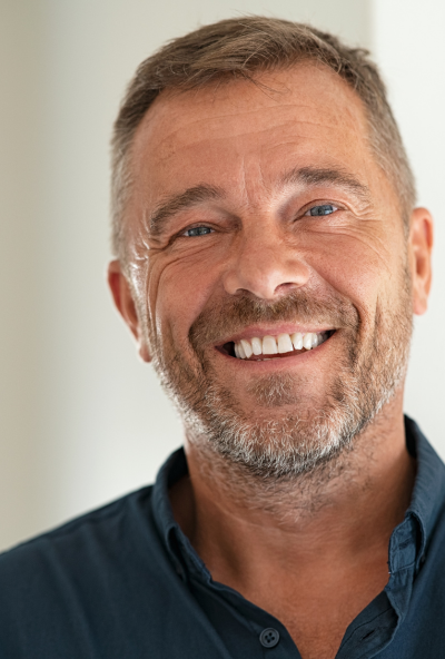 Older male tutor smiles at camera