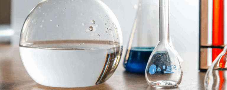 A close-up of laboratory glassware containing clear and coloured liquids, symbolising chemical reactions and scientific investigation.