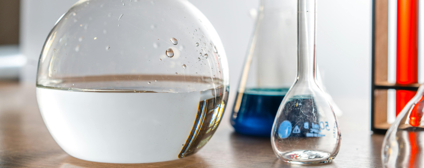 A close-up of laboratory glassware containing clear and coloured liquids, symbolising chemical reactions and scientific investigation.