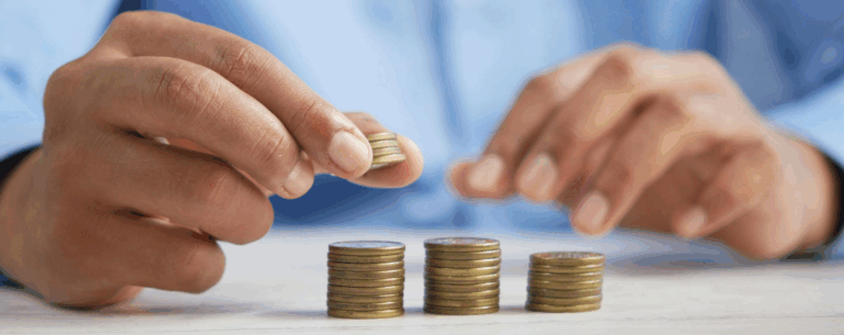 A person stacking coins into piles, symbolising money management, economic systems, and financial decision-making.