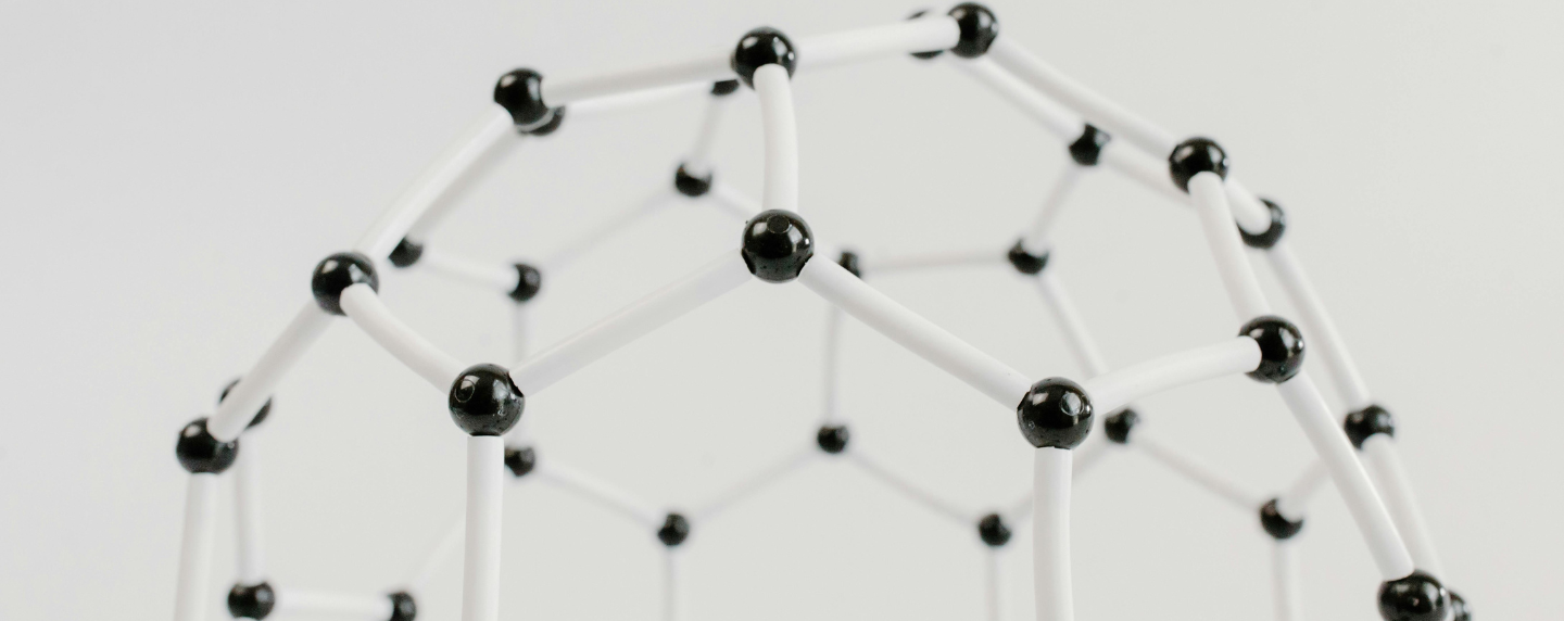 A molecular model showing connected black and white spheres, representing atomic structure and the scientific principles of physics.
