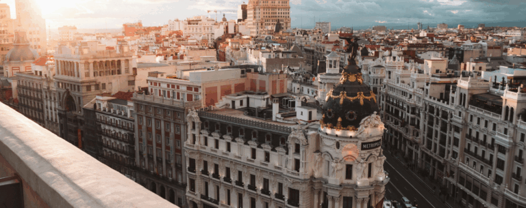 A panoramic view of central Madrid at sunset, featuring the Metropolis building, symbolising Spanish language and culture.