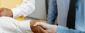 Close-up of diverse professionals shaking hands in a workplace setting, representing leadership, teamwork, and management development.