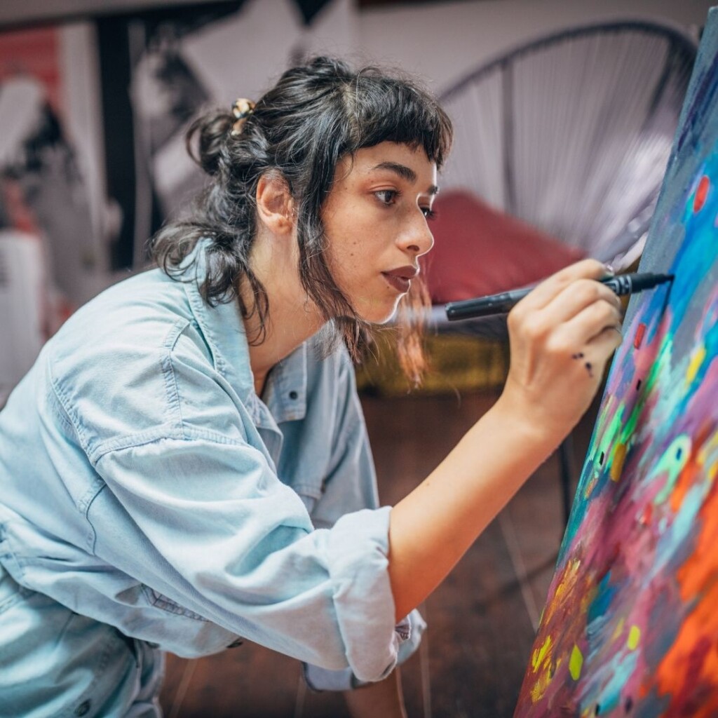 Online creativity and arts courses. Female working on a painted canvas with a marker pen