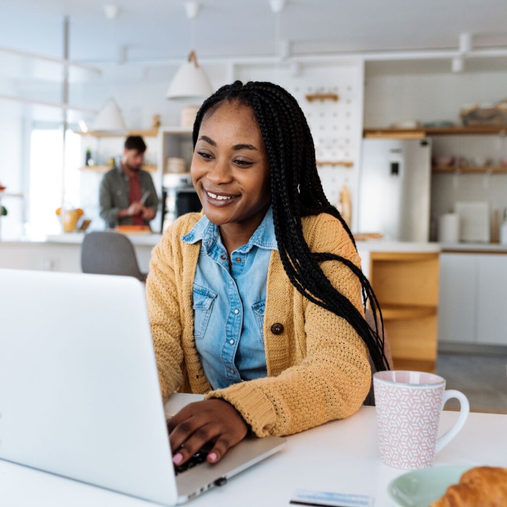 Develop your skills. Femail sat at a laptop in a cafe with coffee and a croissant