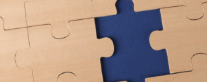 Close-up of wooden jigsaw puzzle pieces with one missing, symbolising the study of human thought and behaviour in A level Psychology.