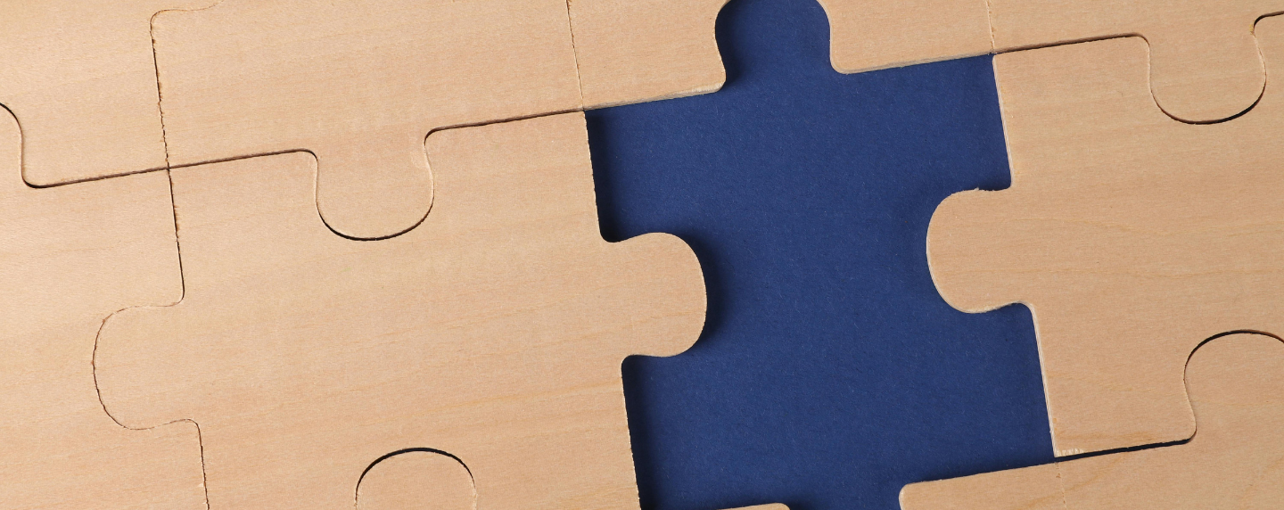 Close-up of wooden jigsaw puzzle pieces with one missing, symbolising the study of human thought and behaviour in A level Psychology.