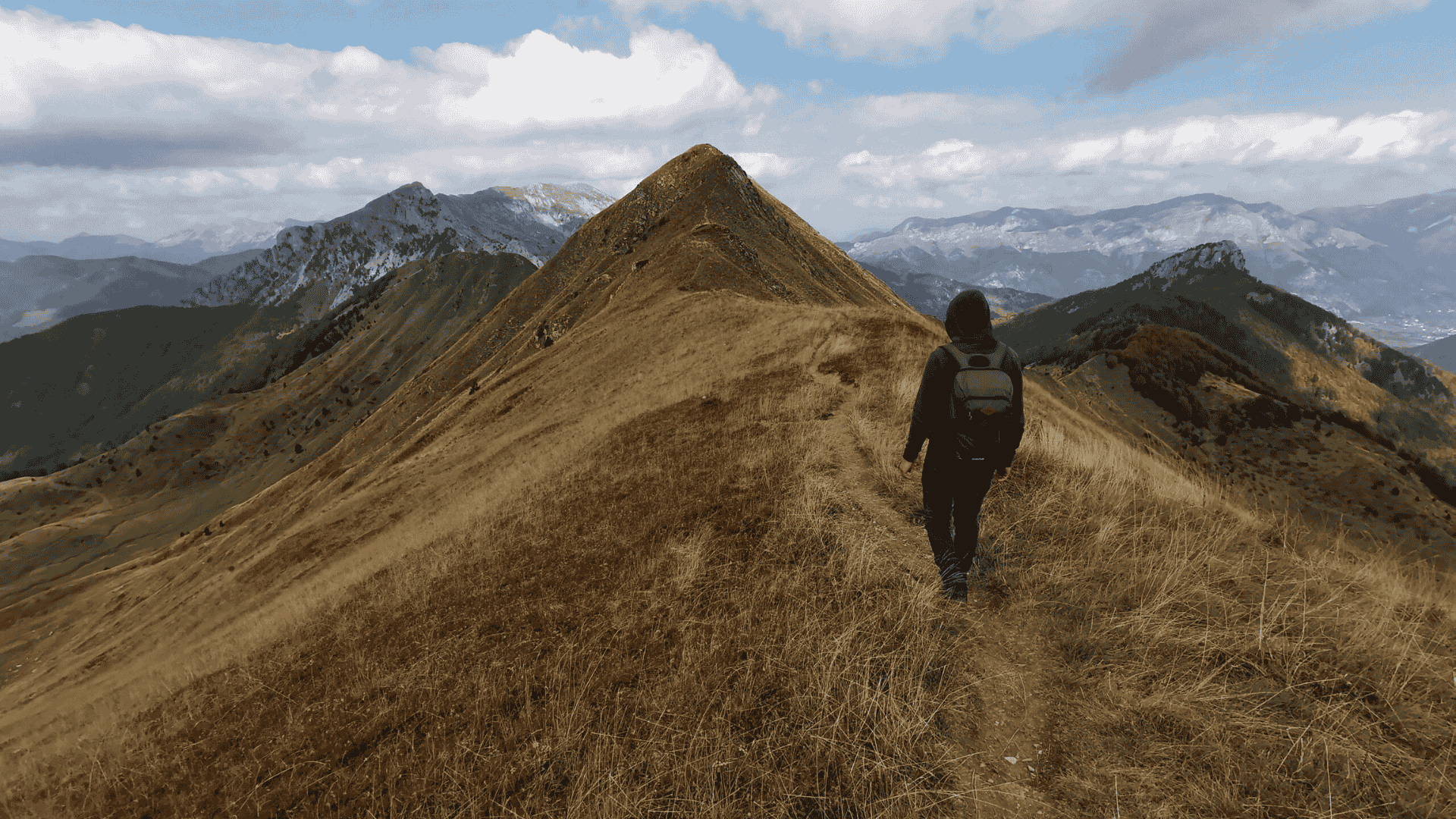 Student hiking alone on a mountain ridge path with scenic views, symbolising the independent path of online learning.