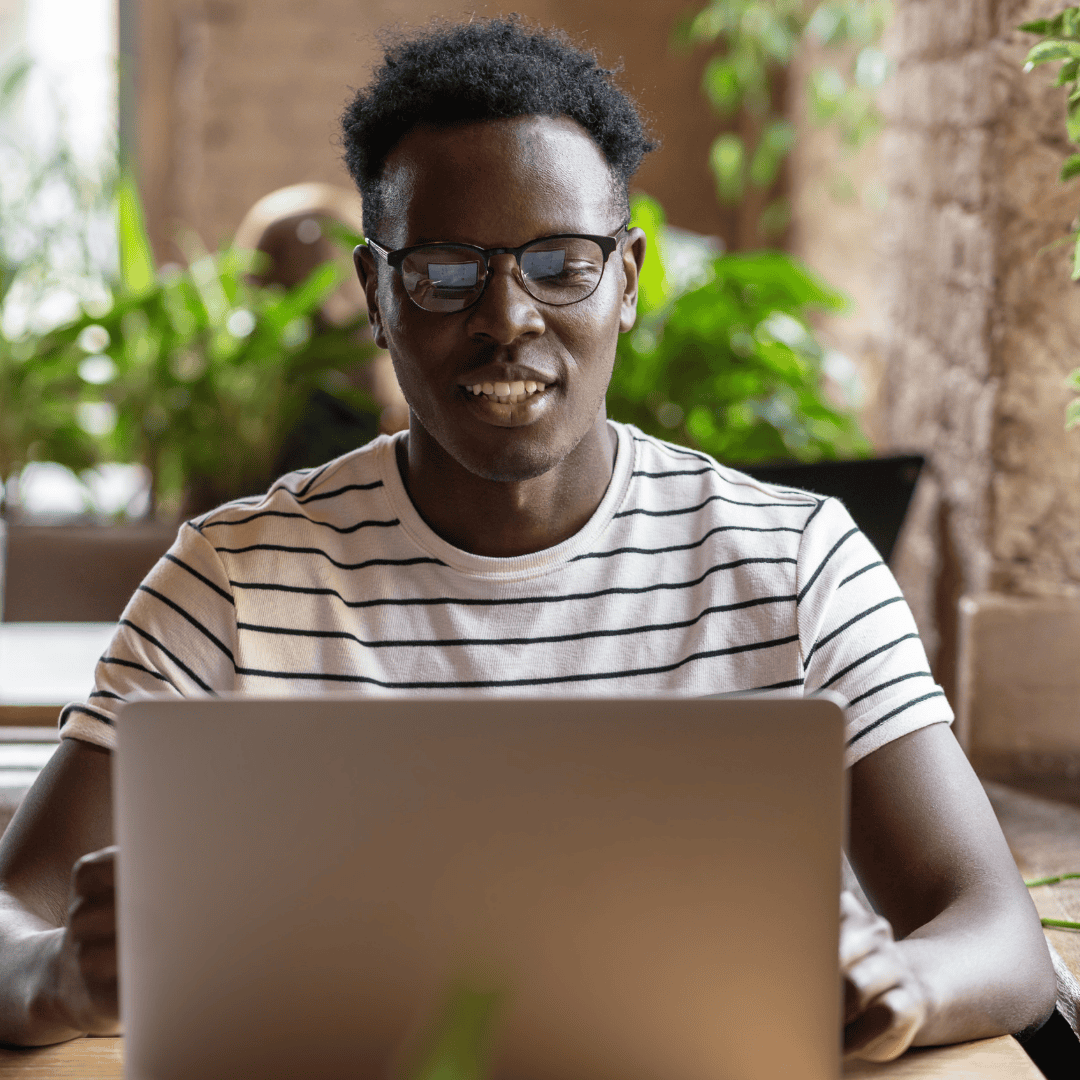 Young man sits studying at his laptop in a cafe