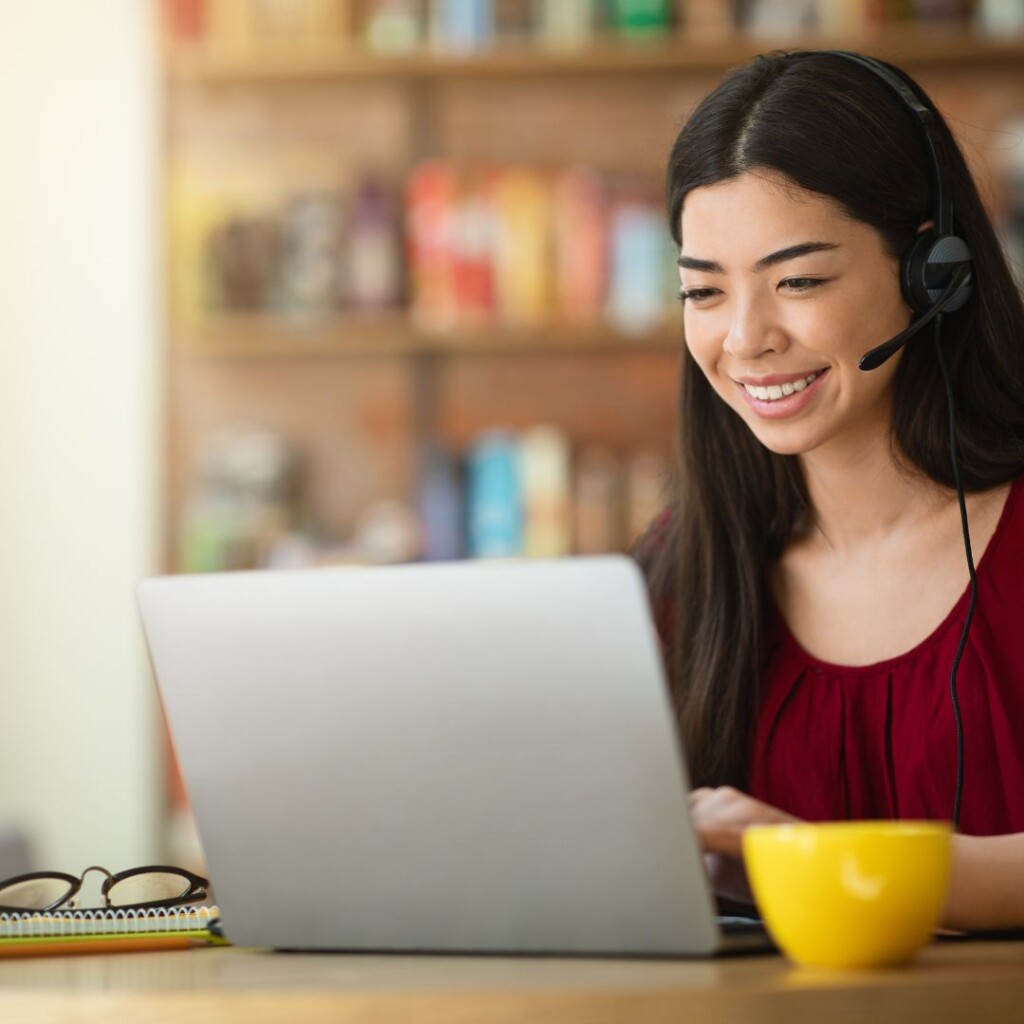Expert online tutors from the NEC. Female on a laptop with headphones on