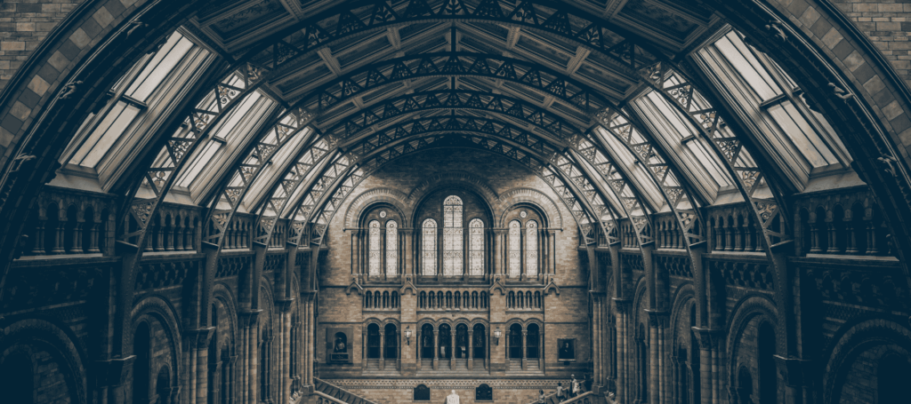 Interior view of a grand historical building with arched architecture and stained-glass windows, representing the study of history and heritage.