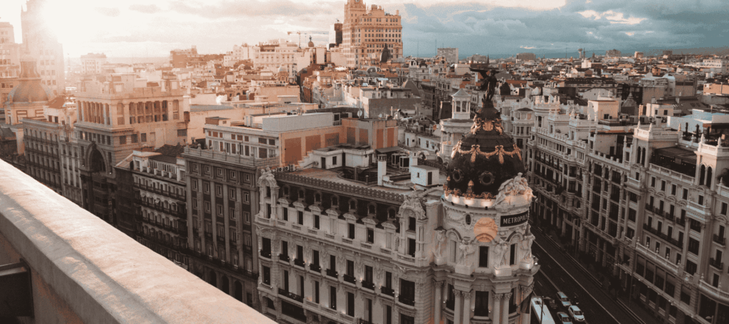 A panoramic view of central Madrid at sunset, featuring the Metropolis building, symbolising Spanish language and culture.