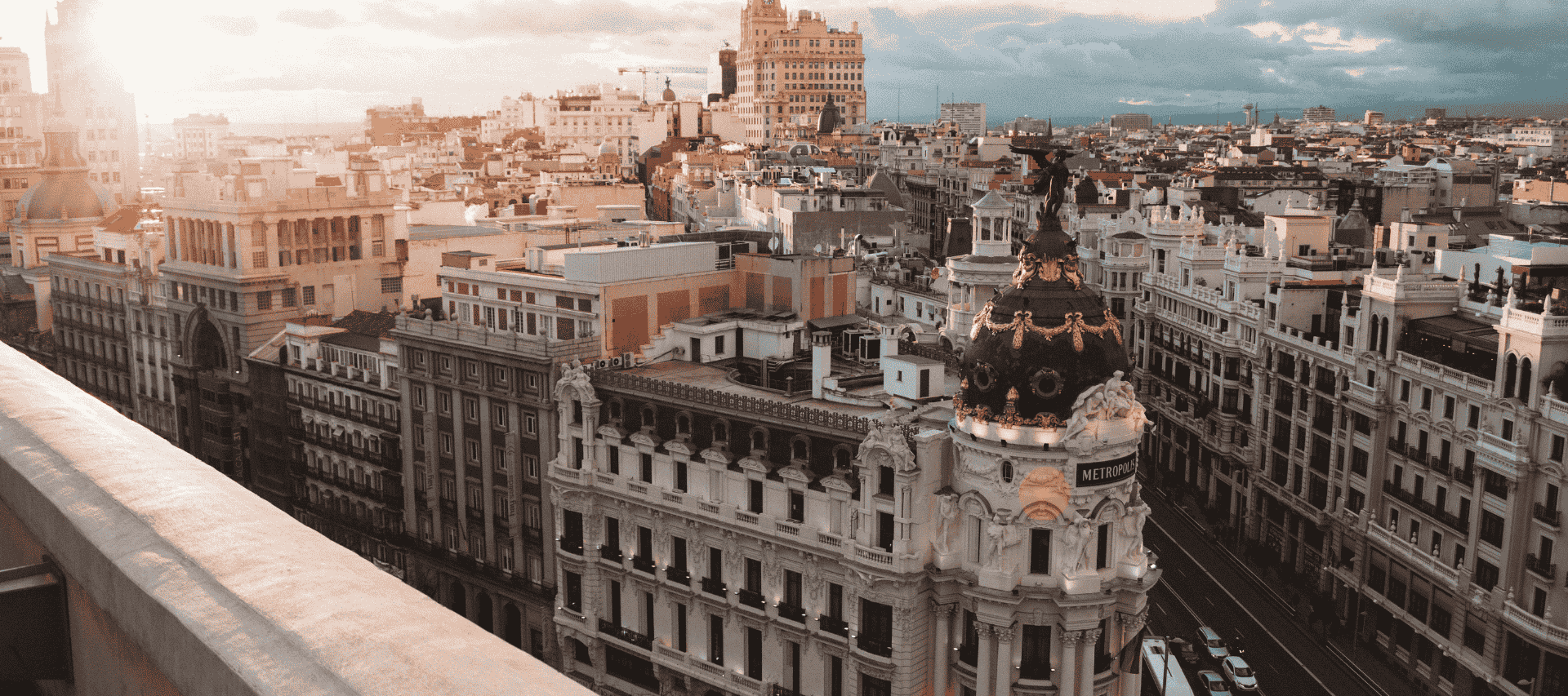 A panoramic view of central Madrid at sunset, featuring the Metropolis building, symbolising Spanish language and culture.