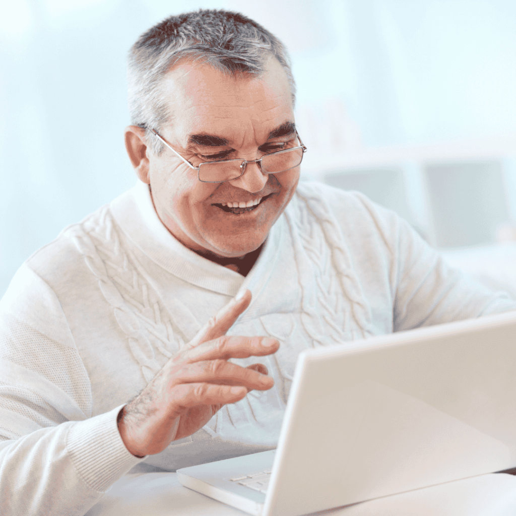 Middle-aged man sits smiling at something on his laptop