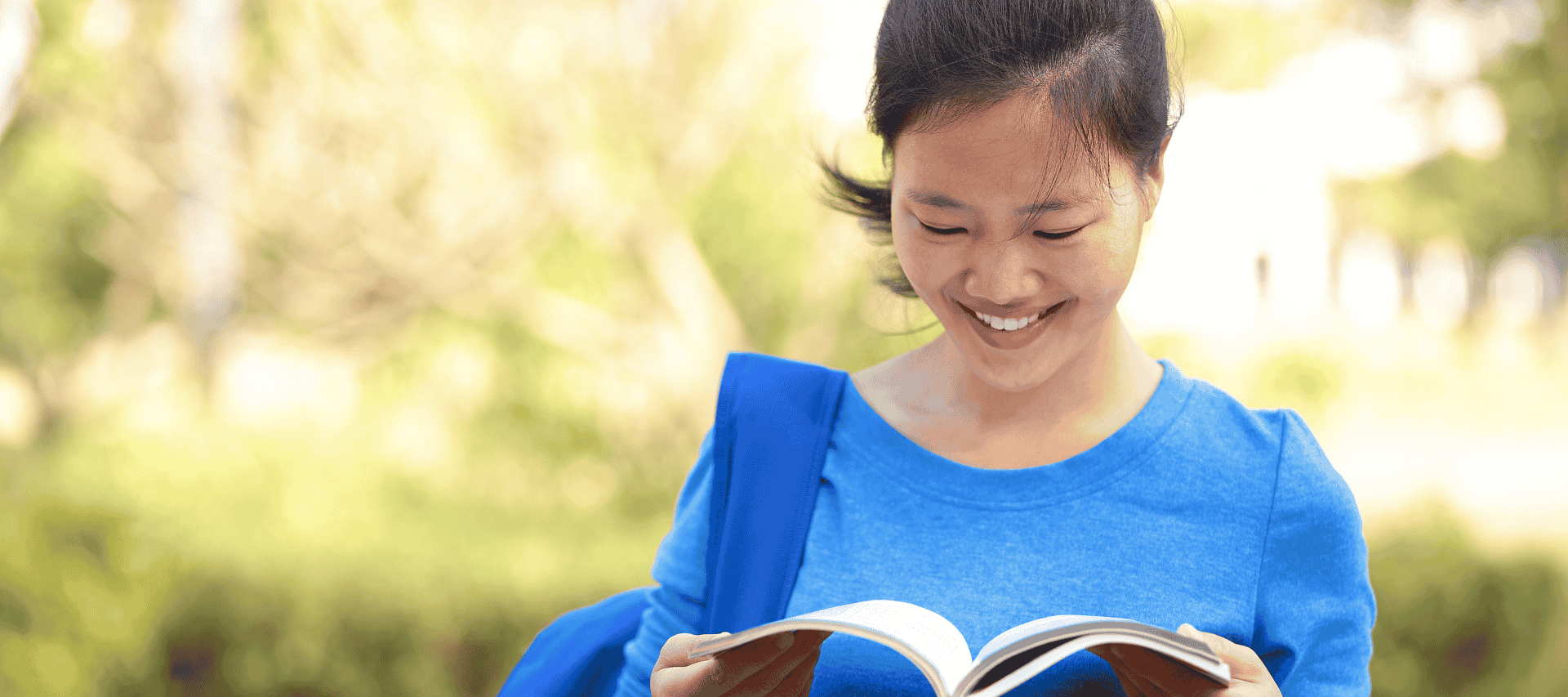 Smiling lady waiting outside smiles as she looks through her study notes.