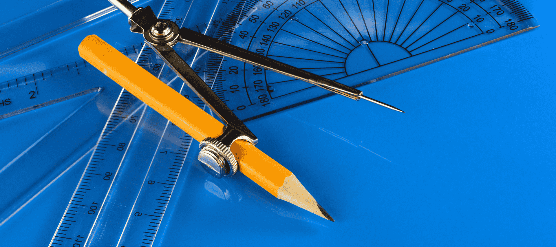 A set square, compass and protractor lay on a desk